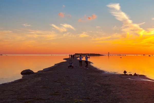 Kleurrijke zonsondergang over zand kust van de zee. Mensen genieten van de dageraad — Stockfoto