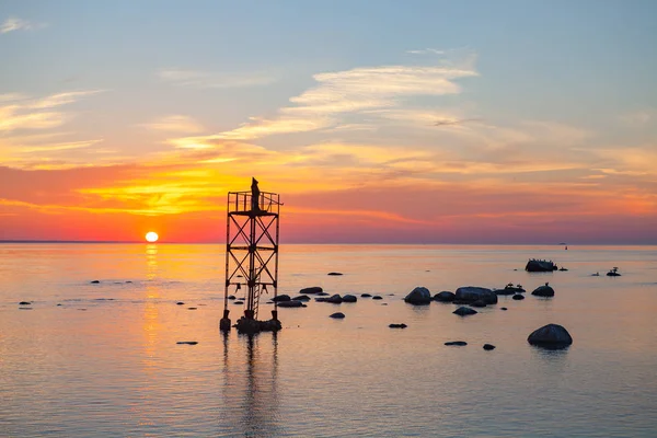 Sunset over sea with magic installation of black monk on the tower