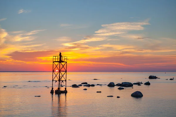 Закат над морем с волшебной инсталляцией черного монаха на башне — стоковое фото