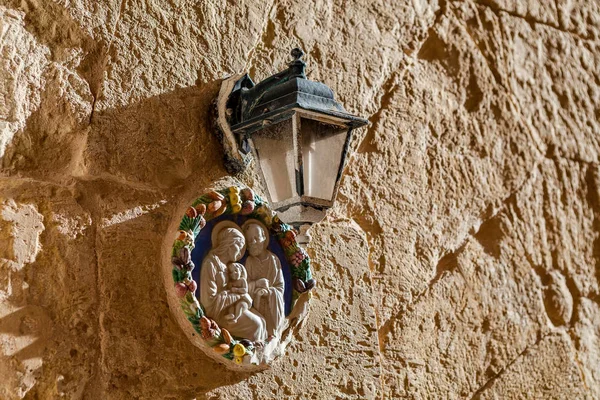 Maagd Maria en een kind. Pictogram onder een lantaarn op een muur van de textuur van een huis aan het mediterrane eiland Malta. — Stockfoto