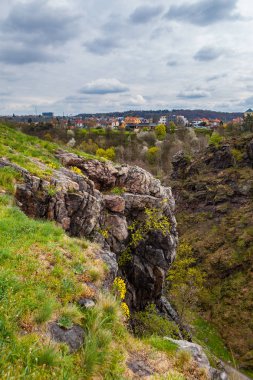 Prag 'daki Divoka Sarka Parkı' nın dik kayalıkları, bahar zamanı. Şehirdeki vahşi doğa parkı. Arka plandaki evler.