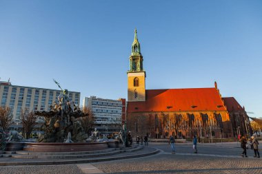 BERLIN, GERMANY - FEBRUARY 21, 2017: St. Mary Church, Marienkirche and ancient fontaine. People walking at sunny day clipart
