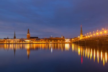 Eski Riga kasabasının silueti gece Daugava nehrinin karşısında taş köprüyle görüldü..
