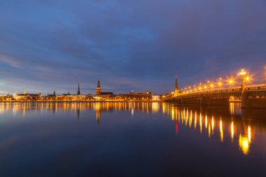 Eski Riga kasabasının silueti gece Daugava nehrinin karşısında taş köprüyle görüldü..