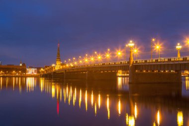 Eski Riga kasabasının silueti gece Daugava nehrinin karşısında taş köprüyle görüldü..