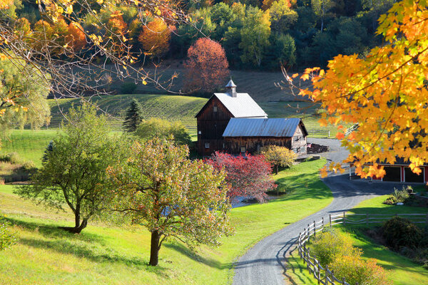 Old barn in Vermont rural side surrounded by fall foliage