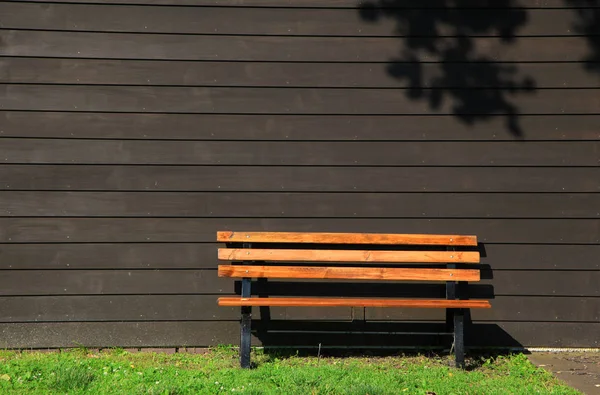Сидячая скамейка у коричневой боковой стены — стоковое фото