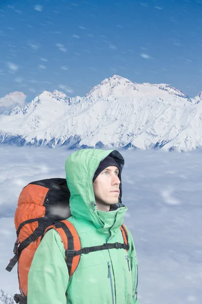 Bergsbestigaren ser på toppen, stående mot en vinter berglandskap. — Stockfoto