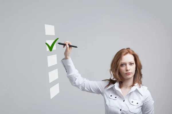 Junge Geschäftsfrau beim Ankreuzen der Checkliste. grauer Hintergrund. — Stockfoto