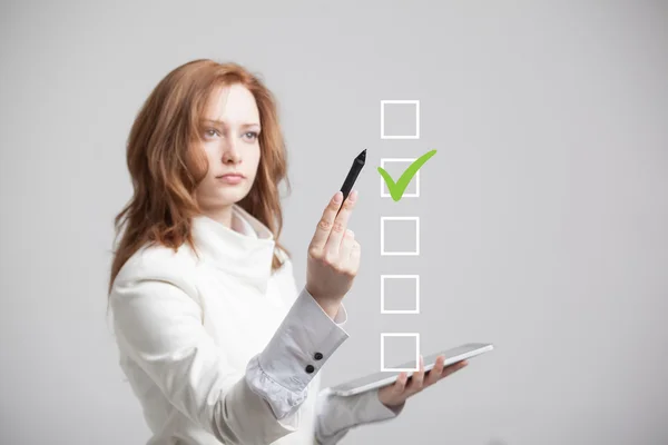 Junge Geschäftsfrau beim Ankreuzen der Checkliste. grauer Hintergrund. — Stockfoto