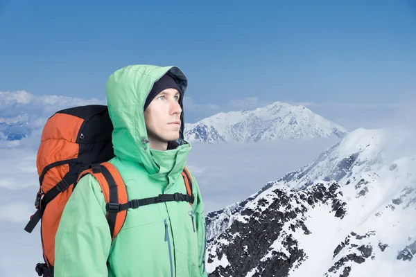 Horolezec se dívá na vrcholu, stojící proti zimní horské krajiny. — Stock fotografie