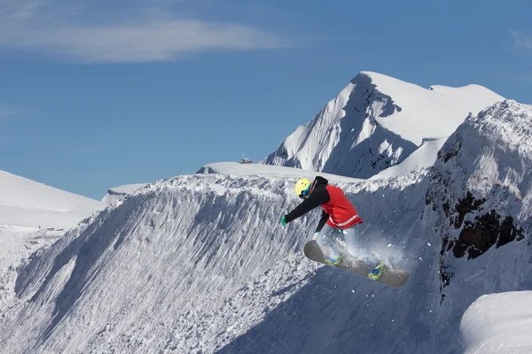 Snowboarder άλμα στα βουνά. Ακραίες σνόουμπορντ freeride αθλητισμού. — Φωτογραφία Αρχείου
