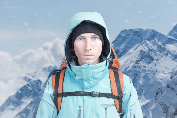Horolezec muž stojí v sněhové bouři, horské krajiny v pozadí. — Stock fotografie