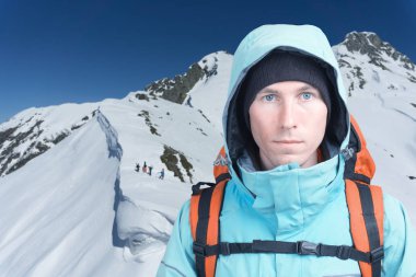 Dağcı adam arka plan yüksek dağlarda kamera bakıyor. Yakın çekim portre.