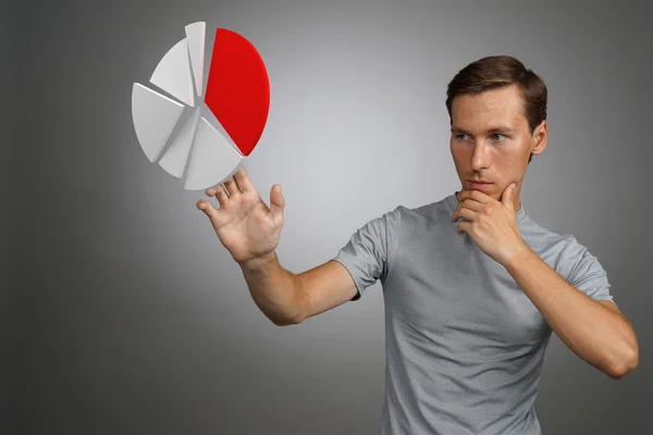 Hombre con camiseta trabajando con gráfico circular sobre fondo gris . — Foto de Stock