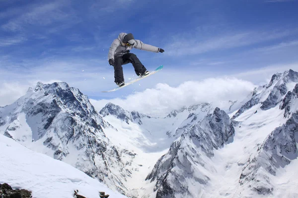 Jeździec na snowboardzie skaczący po górach. Ekstremalne snowboard freeride sportu. — Zdjęcie stockowe