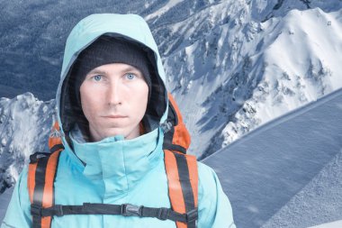 Dağcı adam arka plan yüksek dağlarda kamera bakıyor. Yakın çekim portre.