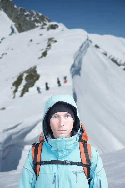 Escalador fica em montanhas de inverno, snowboarders caminhando subida para freeride no fundo . — Fotografia de Stock