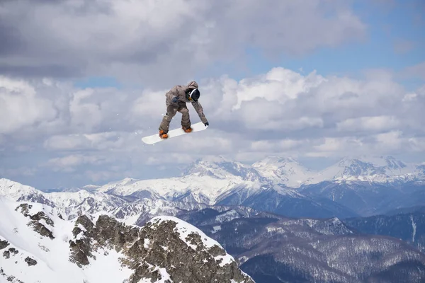 Cavaleiro de snowboard pulando em montanhas. Esporte de freeride de snowboard extremo. — Fotografia de Stock