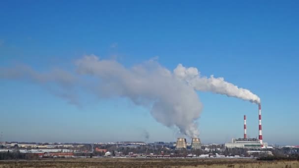Elektrociepłowni lub fabryki z dymiące kominy na horyzoncie. Zanieczyszczających dymu w błękitne niebo. — Wideo stockowe