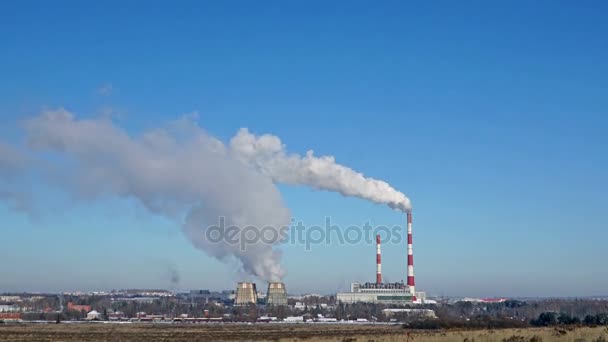 Теплоэлектростанция или завод с дымовыми трубами на горизонте. Загрязняя дым в ясном голубом небе . — стоковое видео