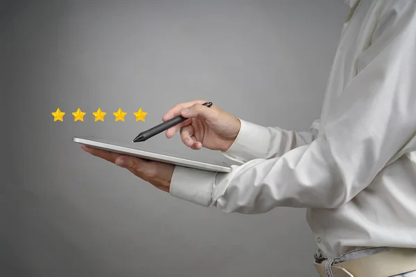 Classificação de cinco estrelas ou classificação, conceito de benchmarking. Homem com tablet PC avalia serviço, hotel, restaurante — Fotografia de Stock