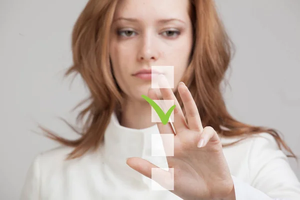 Young business woman checking on checklist box. Gray background. — Stock Photo, Image