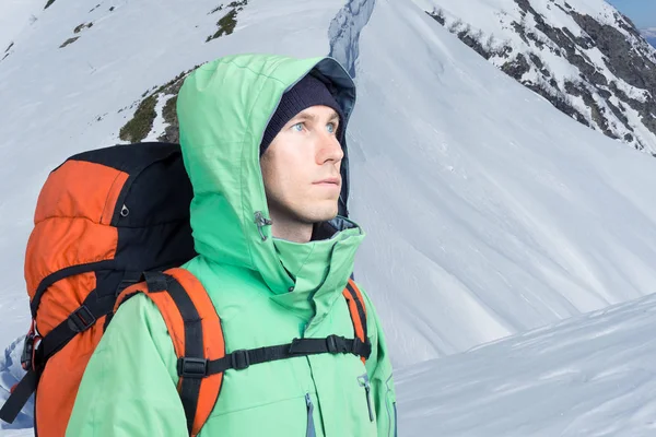 Альпинист смотрит на вершину, стоя против зимнего горного пейзажа . — стоковое фото