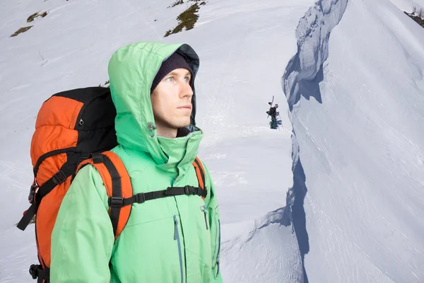 Bergsbestigaren ser på toppen, stående mot en vinter berglandskap. — Stockfoto