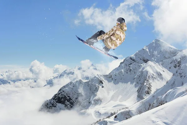 Cavaleiro de snowboard pulando em montanhas. Desporto extremo . — Fotografia de Stock