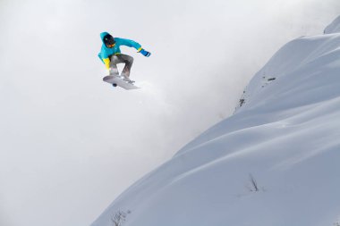 Dağlarda atlayan snowboard binicisi. Ekstrem snowboard serbest spor.