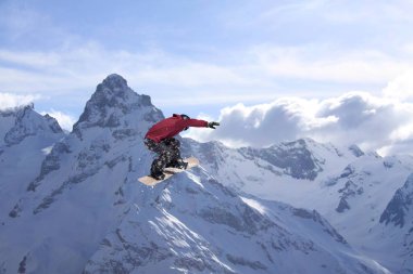 Dağlarda atlayan snowboard binicisi. Ekstrem snowboard serbest spor.