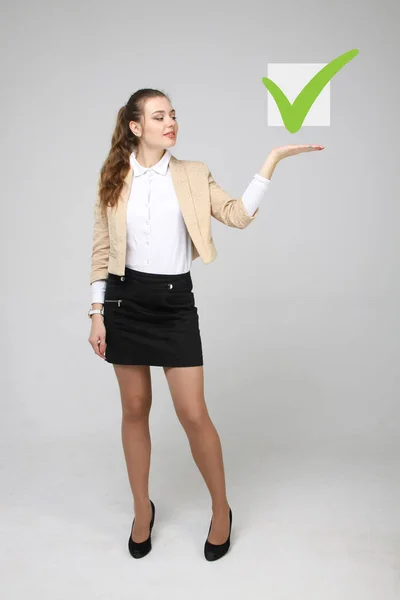 Junge Geschäftsfrau beim Ankreuzen der Checkliste. grauer Hintergrund. — Stockfoto
