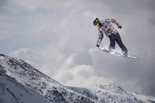 Καβαλάρης snowboard πηδάει στα βουνά. Extreme snowboard ελεύθερο άθλημα. — Φωτογραφία Αρχείου