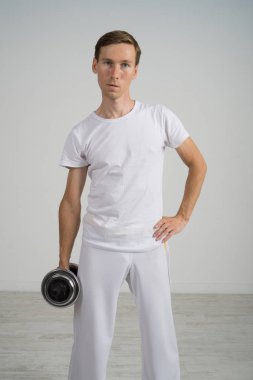 Genç adam dumbbells ile egzersiz yaparak.