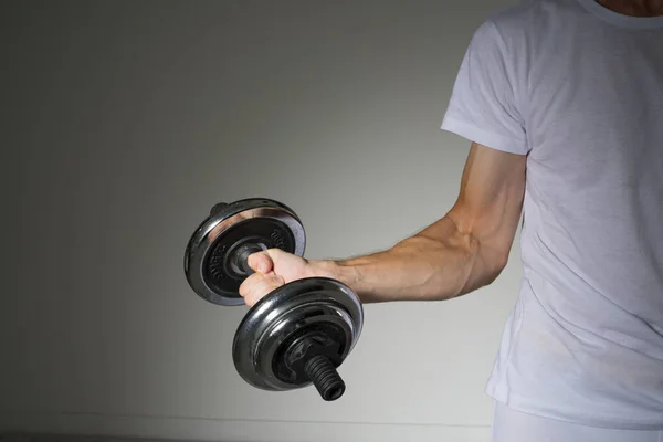 Young Man in a white shirt doing biceps exercises. — Stock Photo, Image