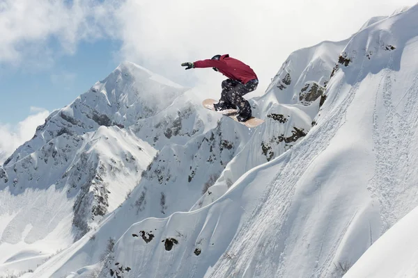 Um snowboarder voador nas montanhas. Extremo esporte de inverno. — Fotografia de Stock