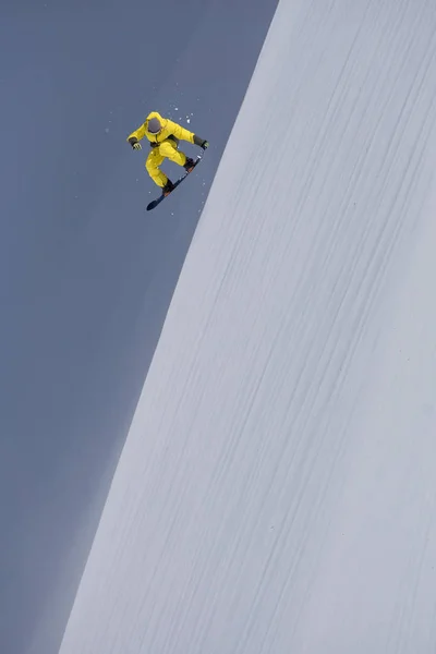 Um snowboarder voador nas montanhas. Extremo esporte de inverno. — Fotografia de Stock