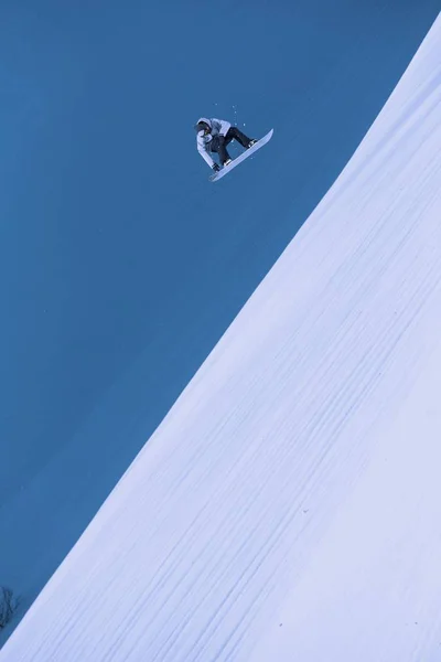 Um snowboarder voador nas montanhas. Extremo esporte de inverno. — Fotografia de Stock