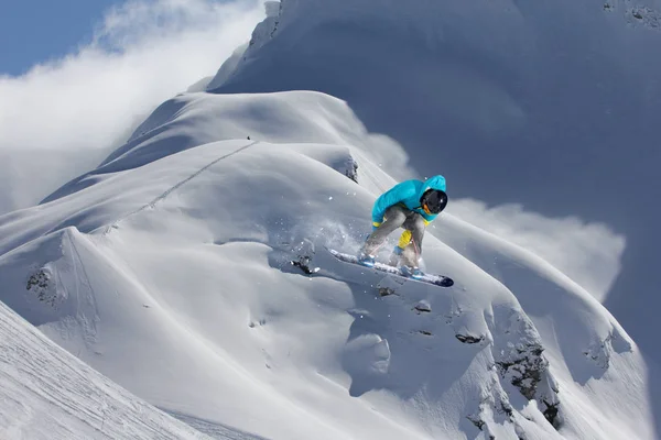 Un deporte invernal extremo. Snowboarder saltando en montañas nevadas . — Foto de Stock