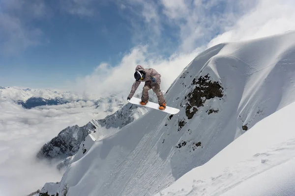 Extreme winter sport. Snowboarder jumping in snowy mountains.