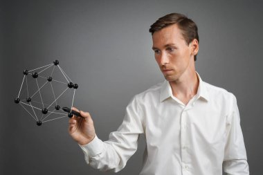 Genç erkek bilim adamı atomun bir modeliyle çalışıyor..