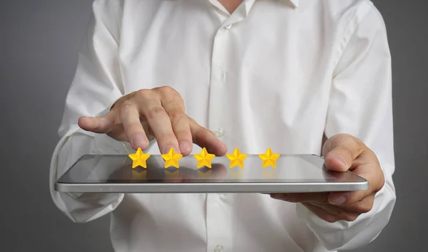 Classificação de cinco estrelas ou classificação, conceito de benchmarking. Homem com tablet PC avalia serviço, hotel, restaurante — Fotografia de Stock