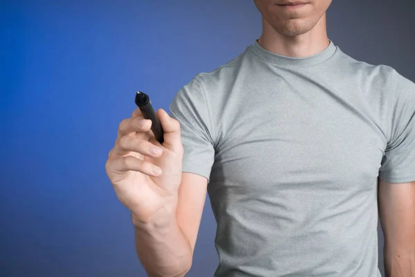 Uomo in t-shirt grigia disegna qualcosa sullo schermo trasparente, su sfondo blu — Foto Stock