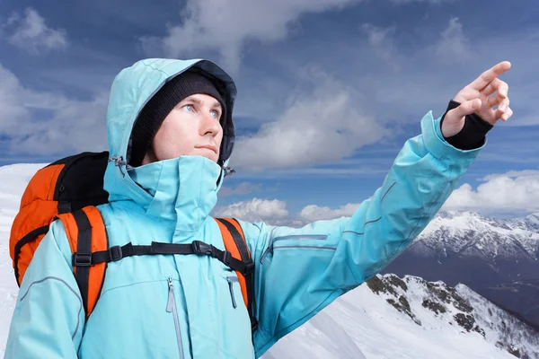 Den bergsbestigare som pekar på topp, stående mot en vinter berglandskap. — Stockfoto