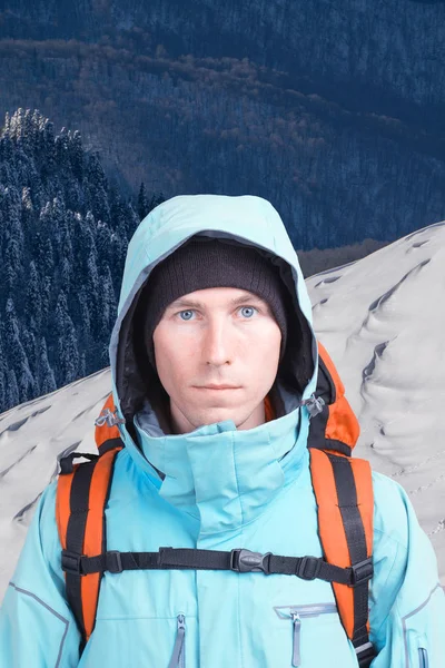 山の風景の背景にバックパックを持つアルピニスト男。カメラを見てください。. — ストック写真