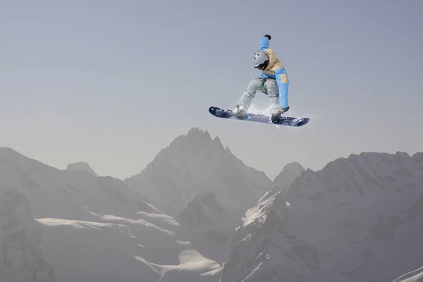 Snowboarder salta en las montañas, deporte extremo de invierno . — Foto de Stock