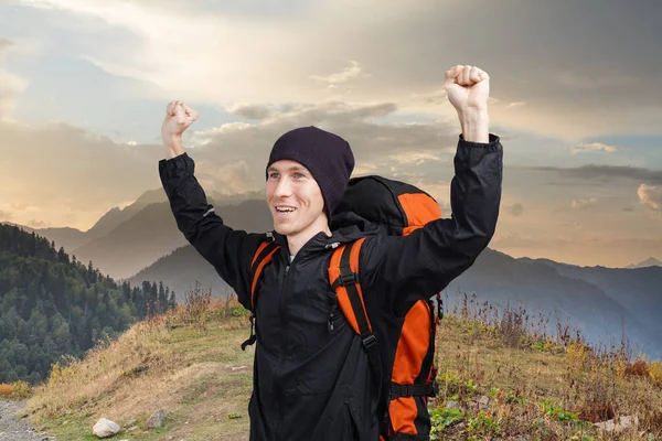 Hombre excursionista con mochila levantó las manos contra un paisaje de atardecer de montaña . —  Fotos de Stock