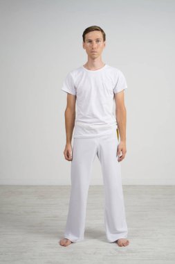 Erkek spor giyim ayakta beyaz oda, tam büyüme portre.