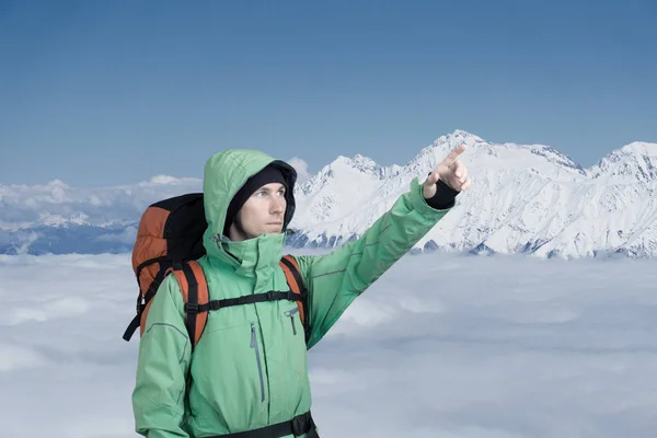 Hombre alpinista mira hacia arriba contra un paisaje de montaña de invierno . — Foto de Stock